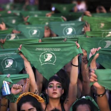 A crowd of women hold up green protest signs