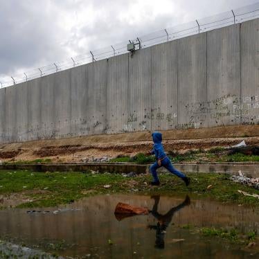 A boy runs alongside a tall concrete wall