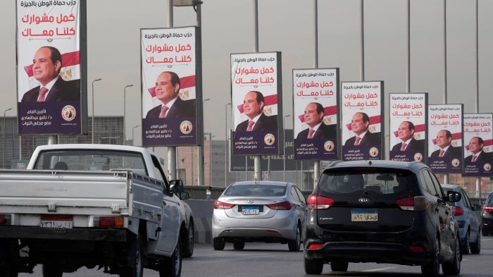 Vehicles pass near banners displaying Egyptian President Abdel Fattah al-Sisi for the presidential elections, in Cairo, Egypt, on December 10, 2023.