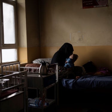 An unidentifiable woman holds her baby son on a hospital bed