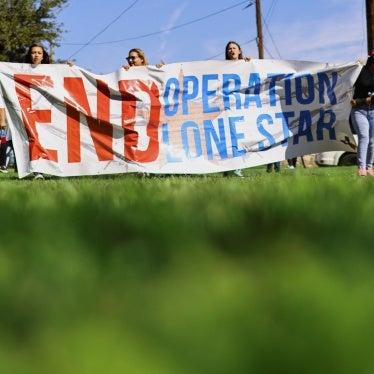 People hold a banner during a protest against Operation Lone Star after members of the Texas National Guard shot and wounded a 22-year-old near the Bridge of the Americas in El Paso, Texas, September 1, 2023. © 2023 REUTERS/Jose Luis Gonzalez