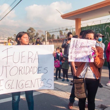 Women hold banners in Spanish at a protest