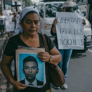 A woman holds a photo of her son at a protest