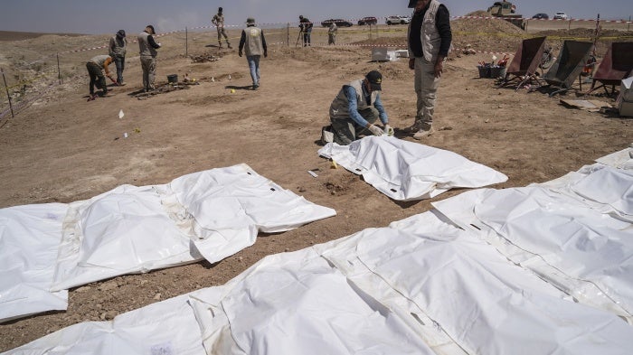 Members of expert teams take part in the opening of a mass grave and the exhumation of the remains of victims who were killed and buried by the so-called Islamic State (ISIS) terror group back in 2014, in Al-Humaydat, Iraq, June 13, 2021.