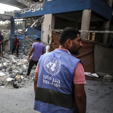 Workers stand in front of the ruins of a school building