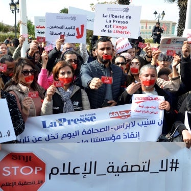 Protesters with red tape over their mouths hold placards