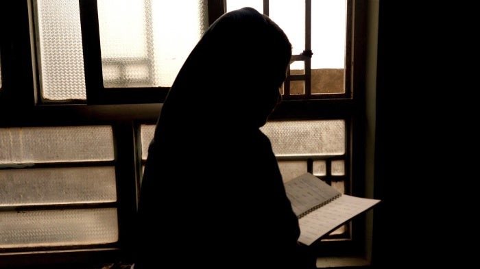 A 15-year-old girl, barred from attending secondary school since 2021, reads a notebook in Afghanistan, March 20, 2024. 