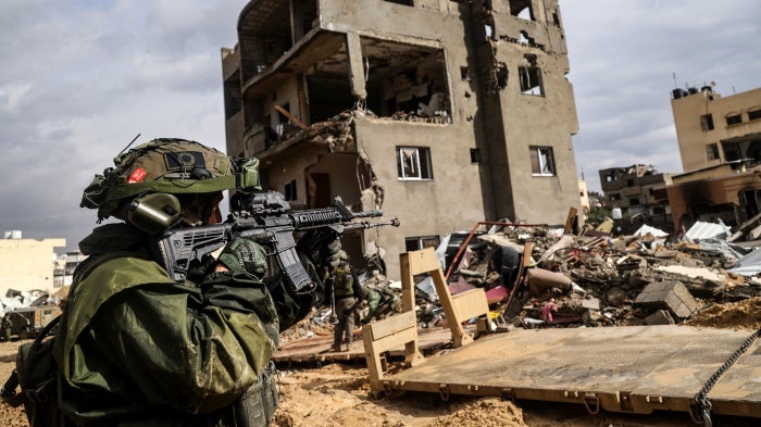 An Israeli soldier aims his weapon in front of a destroyed building in Khan Yunis in southern Gaza on January 27, 2024.