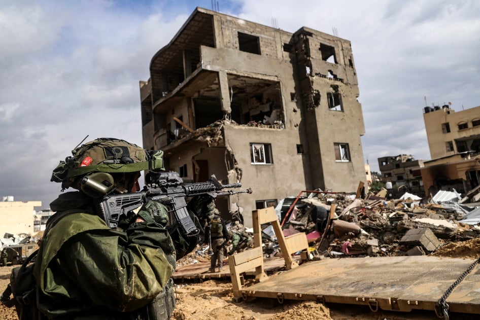 An Israeli soldier aims his weapon in front of a destroyed building in Khan Yunis in southern Gaza on January 27, 2024.