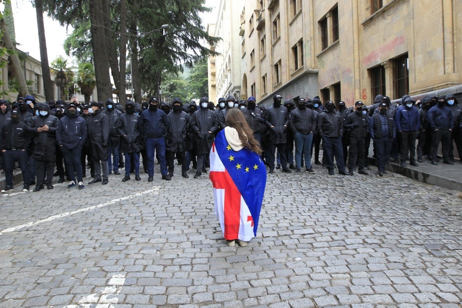 A demonstrator draped with the Georgian national and EU flags stands in front of police who are blocking the way to the parliament building, during a protest against the “foreign agent” law in Tbilisi, Georgia, May 14, 2024.