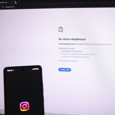 A person holds a phone showing the Instagram logo while a computer screen displays the message “This site can not be reached'”