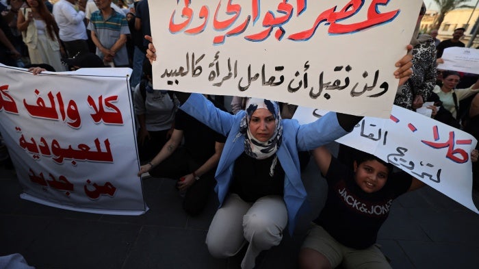 A woman holds a sign protesting women being deprived of their rights in marriage in Tahrir Square, Baghdad, Iraq, August 8, 2024.