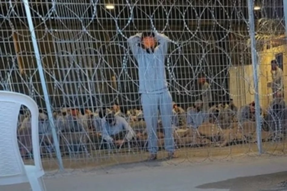 A leaked photograph of the detention facility at the Sde Teiman military base shows a blindfolded man with his arms above his head. Interviewed healthcare workers described this image as punishment imposed by Israeli soldiers on Palestinian detainees if they speak or move. 