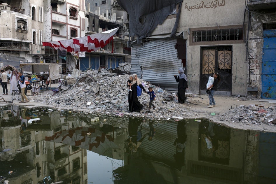 Palestinians displaced by the Israeli air and ground offensive walk next to sewage flowing into the streets of the southern town of Khan Younis in Gaza, July 4, 2024.