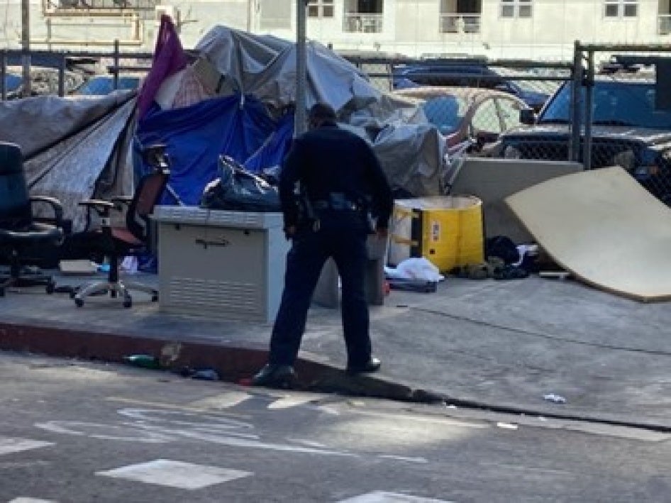 an LAPD officer standing over a tent