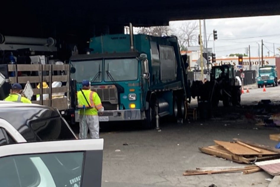 Police next to a tent encampment underneath a highway overpass