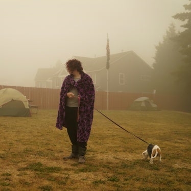 A woman walks her dog at an evacuation center 