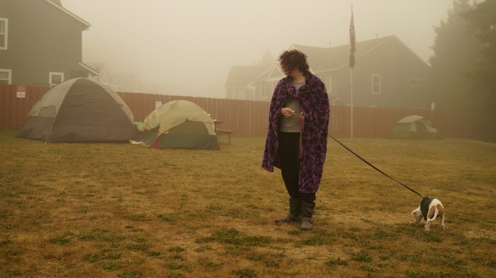 A woman walks her dog at an evacuation center 